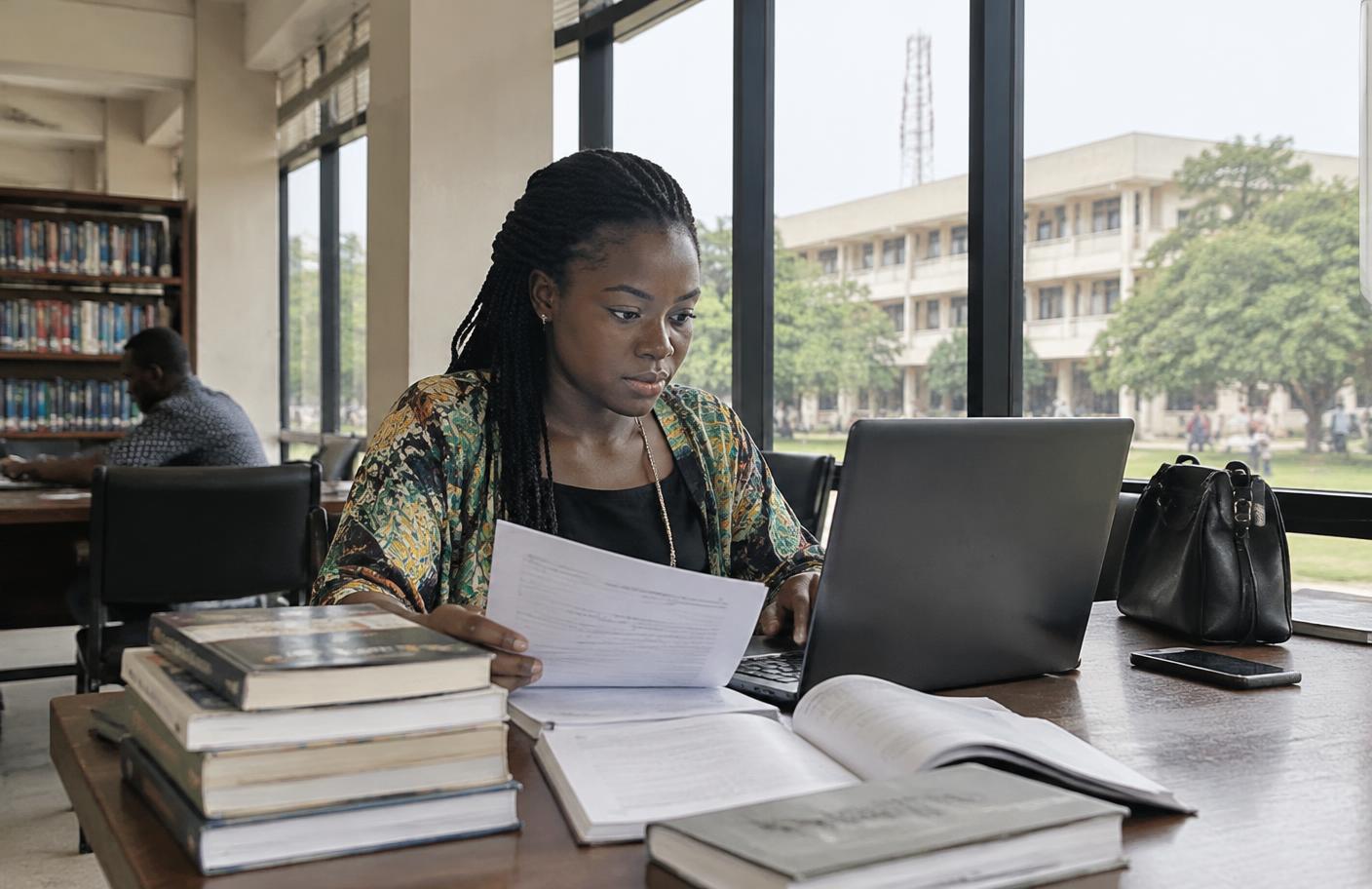 Nigerian researcher working with academic materials in a campus library